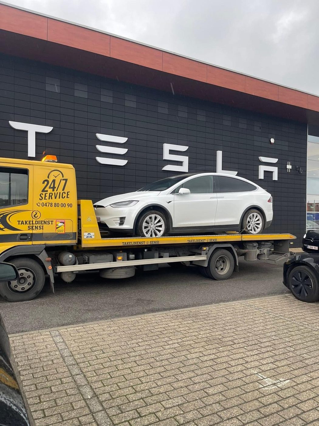 Witte Tesla Model X wordt door Takeldienst Sensi getakeld bij een Tesla-vestiging